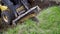 Partial view of mini loader removing layer of grassy soil at earth works