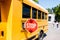 partial view of school bus with stop sign standing on parking with blurred students running