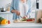 partial view of senior lady cutting mushrooms while cooking dinner at counter in kitchen