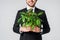 partial view of smiling businessman in suit holding green plant in flowerpot