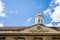 A partial view of the Trinity Hall against a blue sky with partial clouds