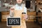 Partial view of waitress holding disposable cup and signboard with open inscription.