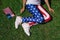 partial view of woman with flagpole in leggins with american flag pattern resting on green lawn, americas independence day