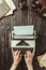 partial view of writer typing on typing machine with blank envelopes and magnifying glasses on wooden tabletop