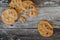 Partially eaten choc chip cookies seen fresh from the oven, on a rustic kitchen table.