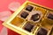 Partially empty box of chocolate candies on red background, closeup