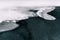 Partially frozen dam pond covered with ice floats snow