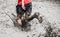 A participant of a physically demanding run is sprinting through the mud