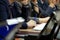 Participants in a business meeting with notebooks, pens, watches, and monitors carefully listen to the speaker. Work time.