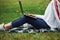 Particle view. Positive girl in casual clothes with her laptop sits on green grass