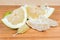 Partly peeled pieces of ripe pomelo on wooden cutting board