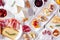 Party appetizers of assorted cheeses, meats and crostini, top view on white wood