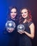 party, emotion and people concept: Two women with disco balls over blue background