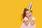 Party time. A joyful cute little child girl in a festive cap and elegant dress celebrates her birthday