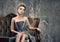 Party time sadness. Lonely beautiful young woman in grey evening dress sitting