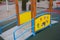 Passage on playground standing with four wooden posts, metal corrugated flooring, riveted blue handrails and painted yellow sides