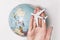 Passenger aircraft on the female palm on the background of the globe. Concept of air travel on a light background