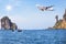 Passenger airplane flying above small limestone island in tropical andaman sea with sunlight.