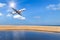 passenger airplane flying above tropical beach in andaman sea on blue sky with sunlight