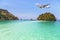 Passenger airplane landing above small island in blue sea