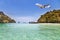 Passenger airplane landing above small island in blue sea and tropical beach