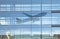 Passenger airplane leaving non existent modern airport seen as reflection in glass facade
