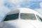 Passenger airplane nose cockpit in blue clouds sky.