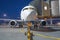 Passenger airplane is parked connected by a ladder at the terminal building in the airport, near the front trailer winch for tow