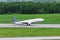 Passenger airplane takes off from the runway against the green forest