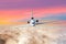 Passenger airplane with three engines on the tail flying above the clouds horizon sky with bright sunset colors., the view is exac