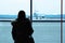 Passenger in the airport, silhouette of a woman looking at the plane on the tarmac through the glass