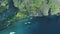 Passenger boats at rock ocean shore aerial view. Green forested mountain ranges of Palawan Island