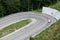 Passenger car pivoting movement at asphalt mountain hairpin road, aerial view