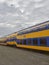 Passenger carriages from Dutch Urban Railway Companies in a line on tracks at a Container Terminal in Den Haag.