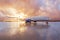 Passenger commercial wide-body aircraft parked with a wet apron at the airport during evening rain at sunset with beautiful sky