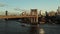 Passenger cruise ship passing under Brooklyn Bridge. Fly above calm river. Urban neighbourhood in background. Brooklyn