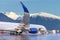 Passenger jet airliner in the parking lot preparing for departure against the backdrop of picturesque snow-capped mountains in the