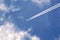Passenger jet flying in blue sky with clouds leaving white trail