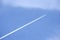 Passenger jet flying in clear blue sky, leaving white trail