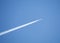 Passenger jet flying in clear blue sky, leaving white trail