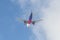 A passenger plane comes in for landing, releasing the landing gear against the background of a blue sky with clouds.