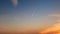 Passenger plane flying in the blue sky at sunset, fast transport vapor trails