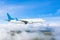 Passenger plane with landing gear lowered before boarding at the airport on a background of clouds and blue sky