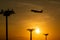 Passenger plane is takeoff during a beautiful sunrise. Lamp tower of spotlights on the pillars at the airport