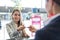 Passenger service agent giving woman`s passport and boarding pass in check in area at airport