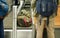 Passenger standing next to checked in bags and luggage on transport belt of airport check-in desk, view from behind