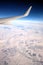 Passenger supersonic plane wing moving high from right to left in blue cloudless sky above snow filds far on the ground