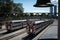 Passenger trains traveling through a bustling train yard with a clear blue sky in the background