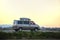 Passenger van with roof rack driving fast on intercity road at sunset. Highway traffic in evening