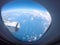 Passenger view through the window of a jet plane showing sky, clouds, jet engine and wing